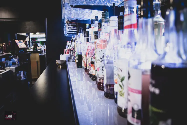 Bar lounge du 113 Avenue, club libertin à Eysines près de Bordeaux, tabourets et éclairage néon.